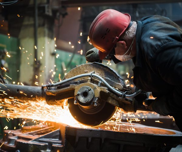 Worker grinding metal, metal grinding machine with sparks, metal sawing